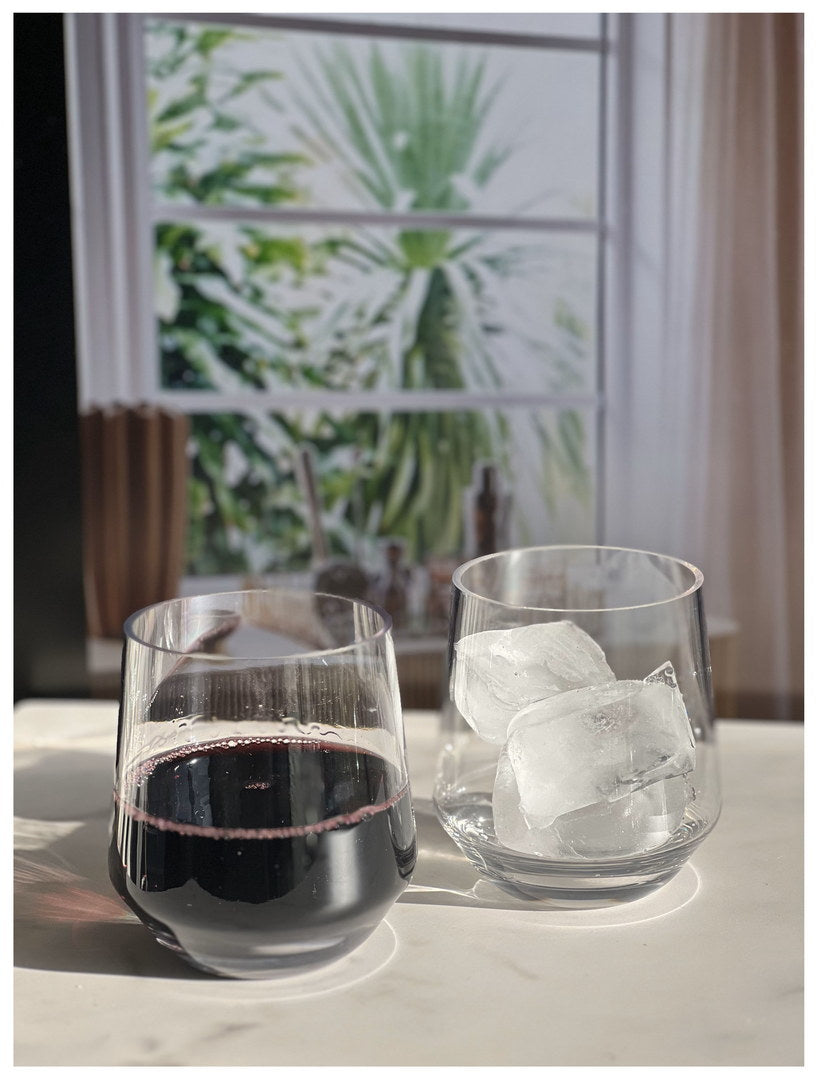 Clear wine glasses with dark red wine and visible ice cubes