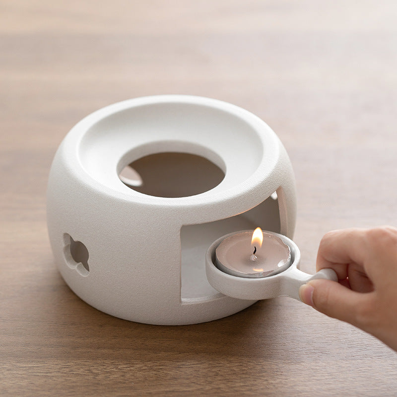 White ceramic heating pot with candle flame inside, warm surface holder