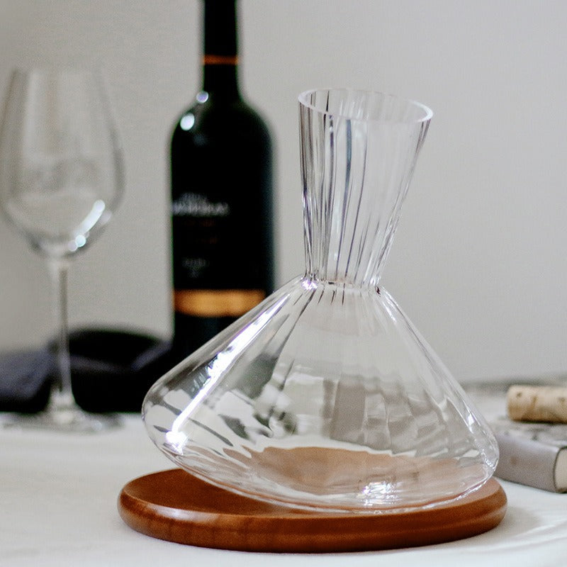 Crystal wine decanter with fluted body, amber wine inside, on wooden tray