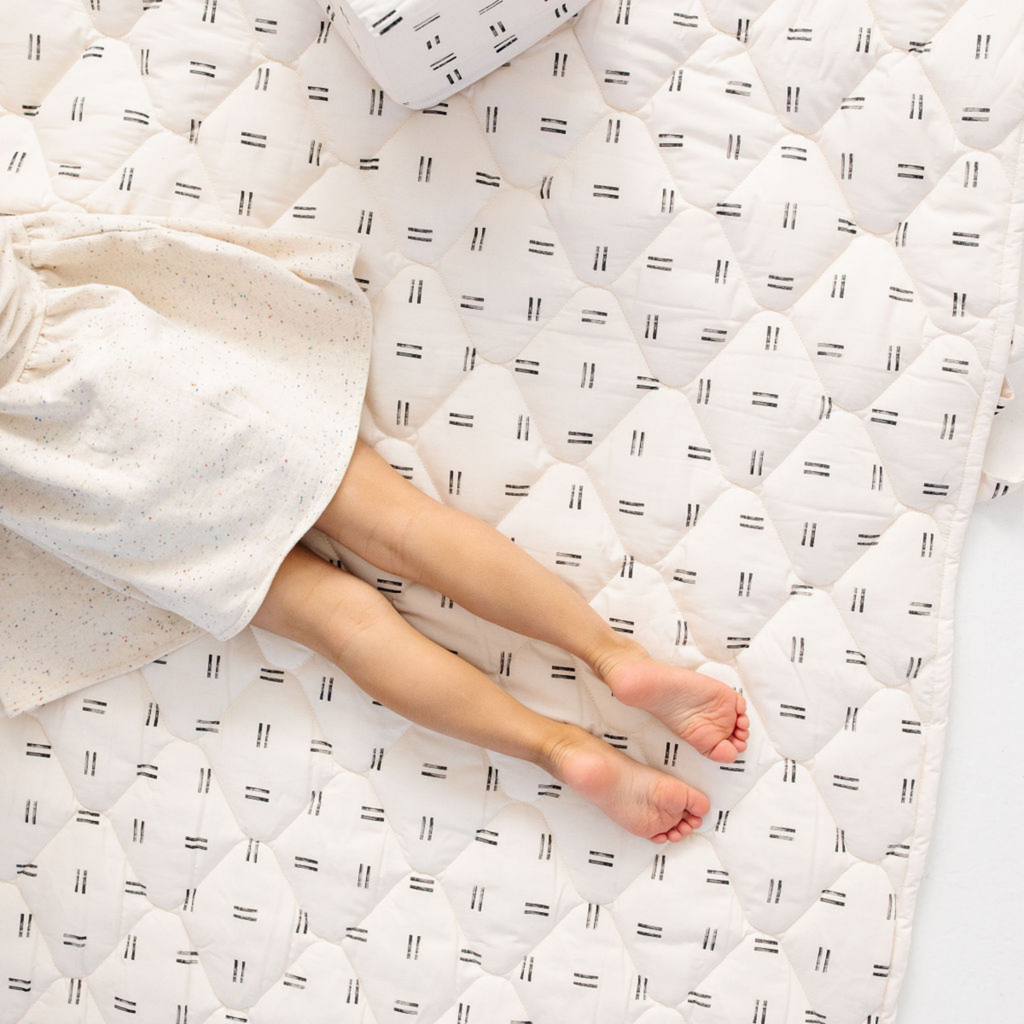 Off-white waterproof picnic blanket with repeating black mudcloth pattern, beige speckled fabric edge