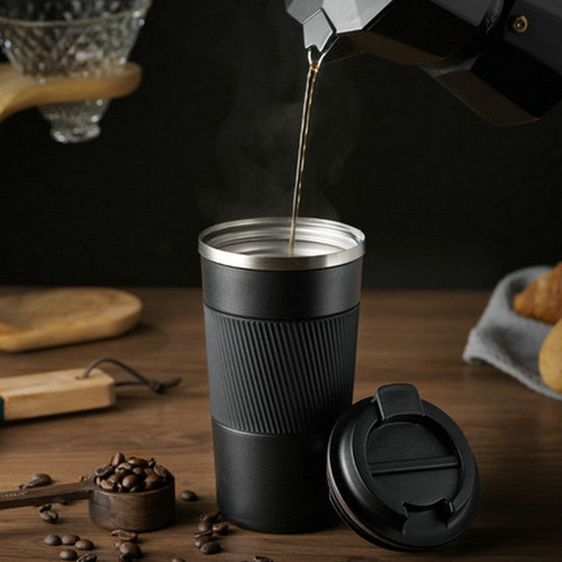 Black insulated travel mug with ribbed sleeve, open flip-top lid while coffee is poured