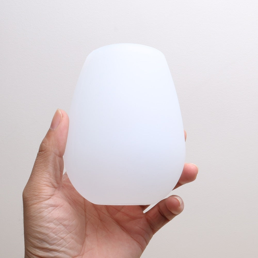 Foldable silicone wine cup, white, held in hand while collapsed