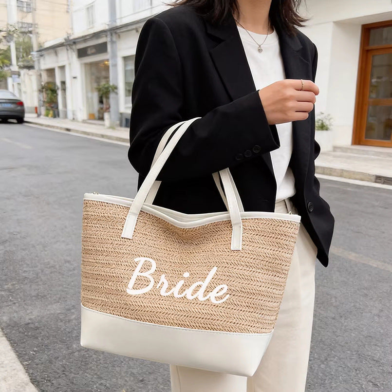 Light khaki woven tote bag with 'Bride' cursive, white bottom, long handles