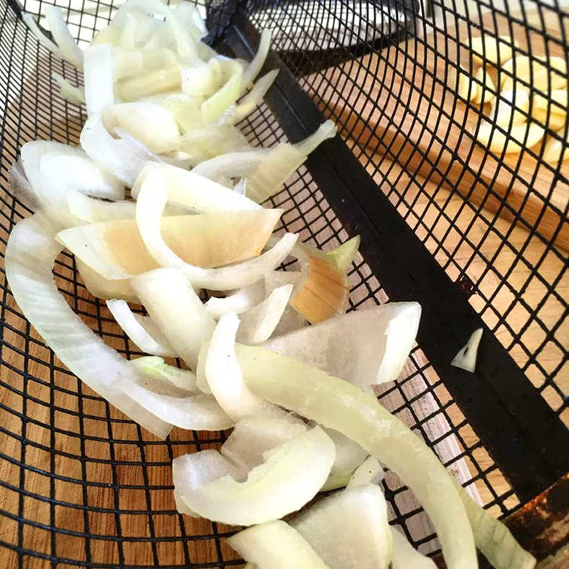 Mesh grilling basket filled with sliced onion and vegetable pieces for grilling.