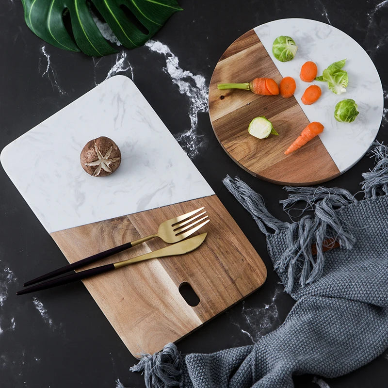 Wood-and-marble charcuterie board with serving notch and handle cutout, shown with utensils