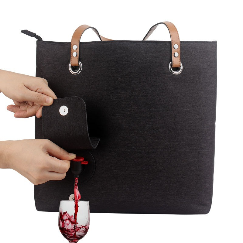 Insulated wine picnic tote bag in dark fabric with tan handles and front pocket, with wine glass